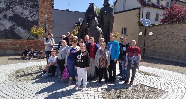 grupa uczestników stoi przy pomniku